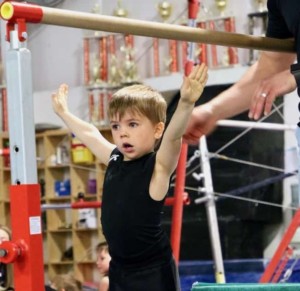 4 year old boy performing on gymnastics bars