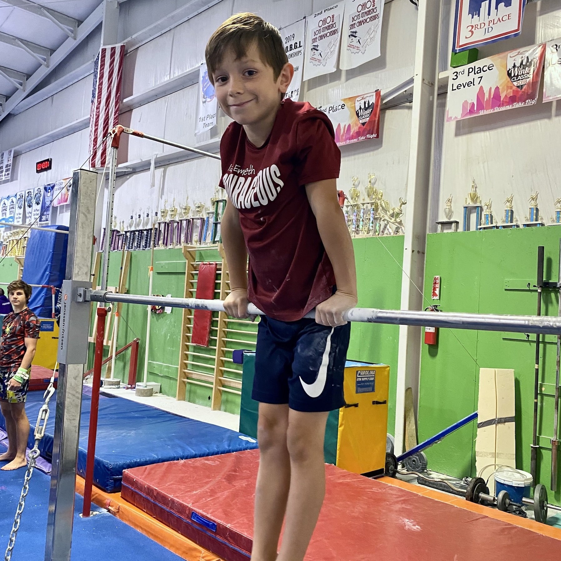 Confident boy on bar in gymnastics class