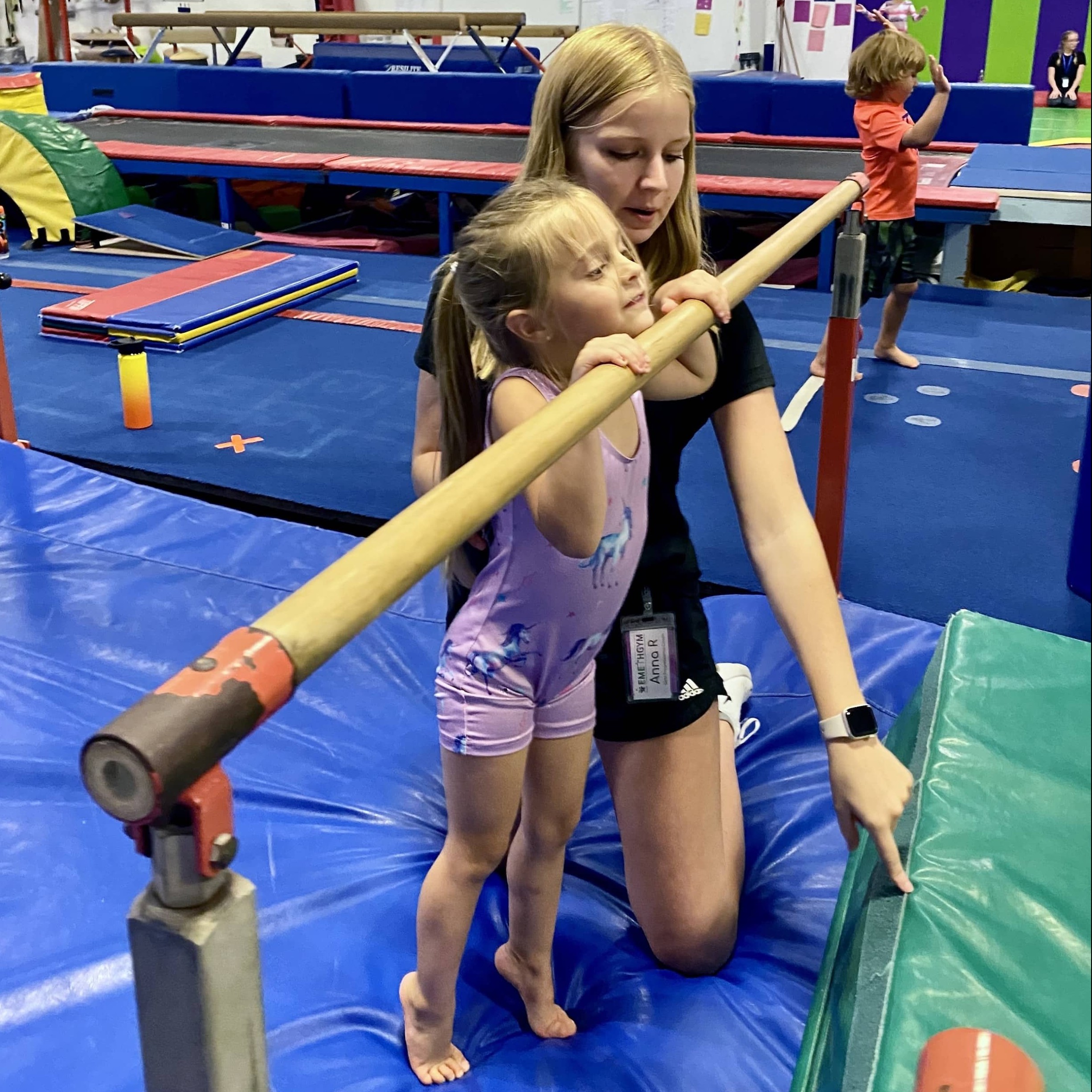 Caring coach with young girl on bars